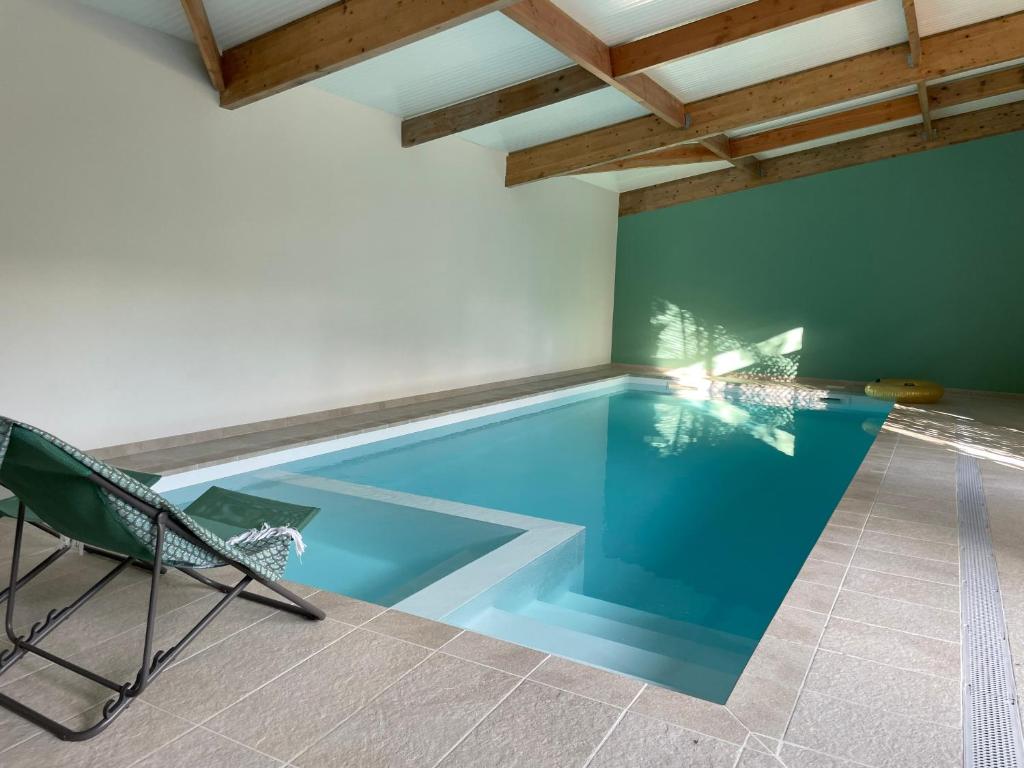 una piscina con una silla y una mesa en Villa La Luciole Piscine interieure, en Barneville-Carteret