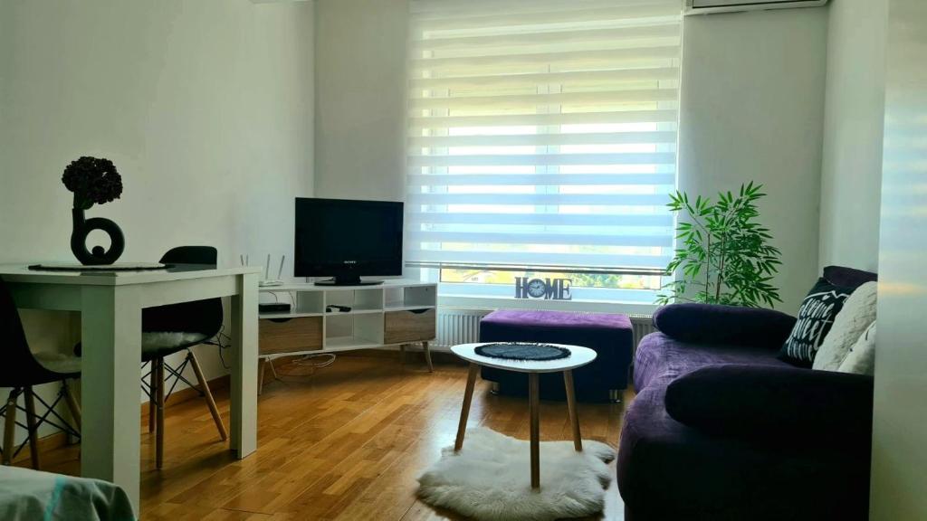 een woonkamer met een paarse bank en een tafel bij RELAX LuX 2 in Jagodina