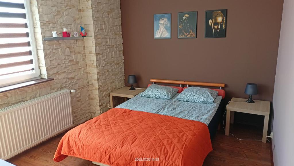 - une chambre avec un lit doté d'une couverture orange et d'oreillers bleus dans l'établissement Pokoje Gościnne JAK W DOMU Hanna Kucharska, à Sztutowo