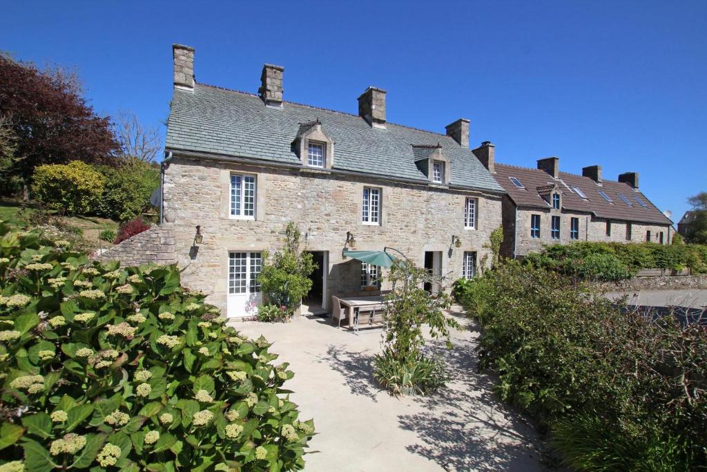 uma antiga casa de pedra com um jardim em frente em gite des vieilles rues em Omonville-la-Rogue