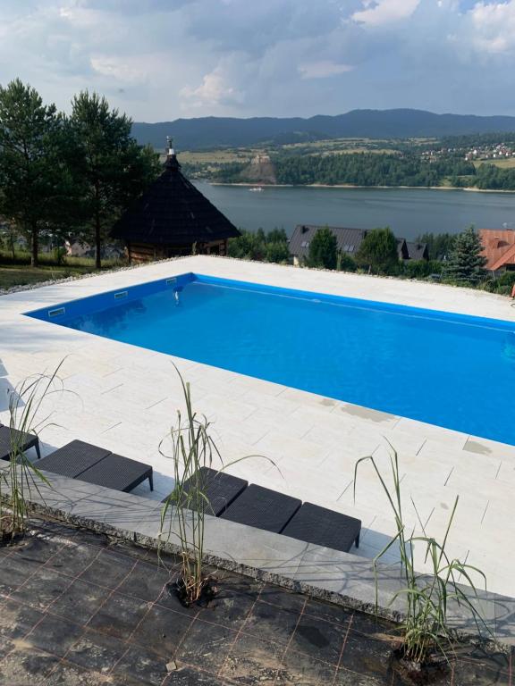 een blauw zwembad met uitzicht op een meer bij Mergen Bike & Ski Resort in Niedzica Zamek