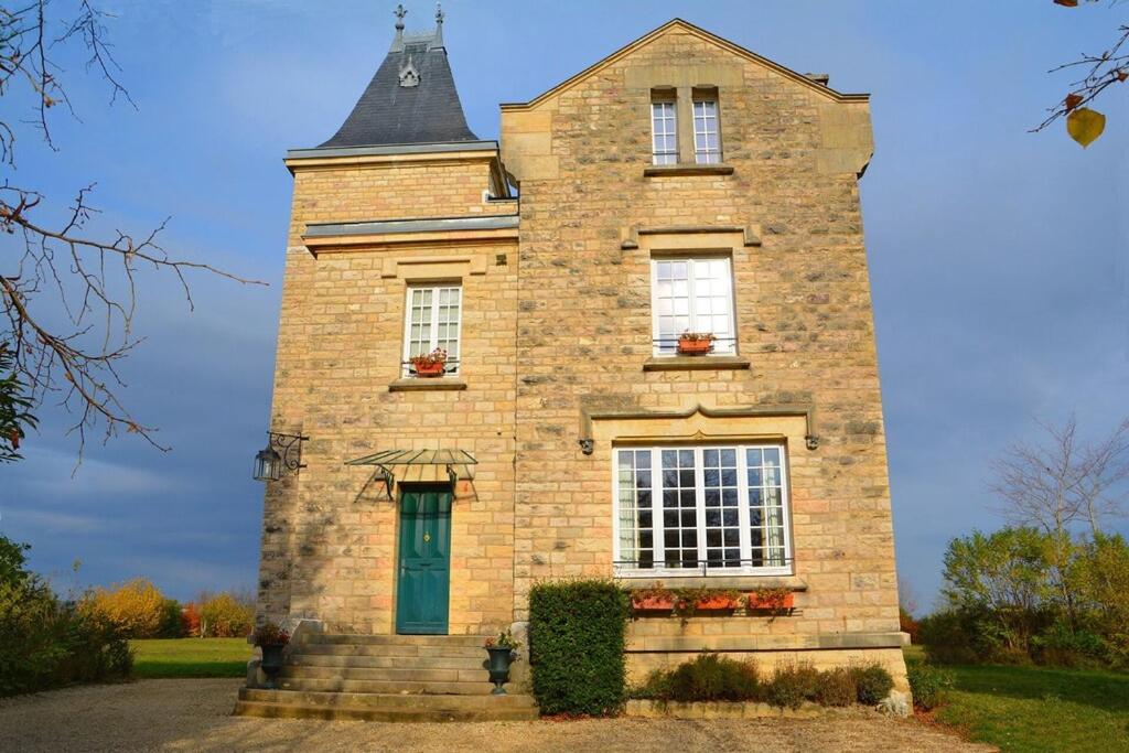 un grand bâtiment en briques avec une porte verte dans l'établissement Chateau des Barrigards, à Ladoix Serrigny