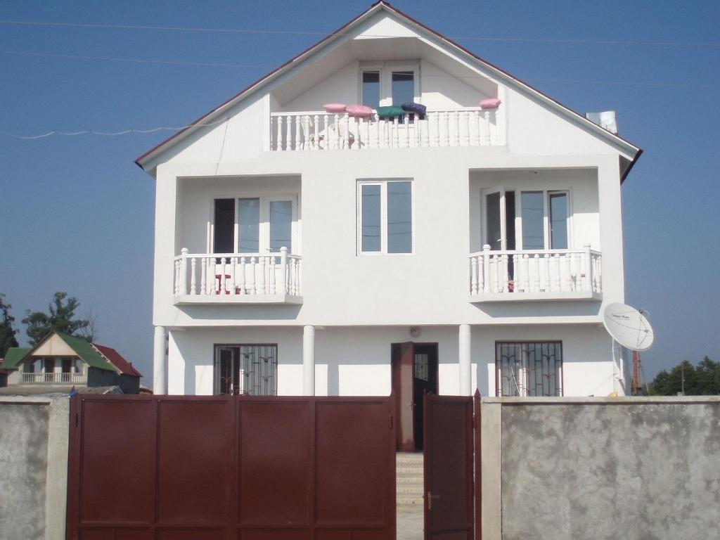uma casa branca com uma cerca à frente. em Large house at the beach. em Grigoleti