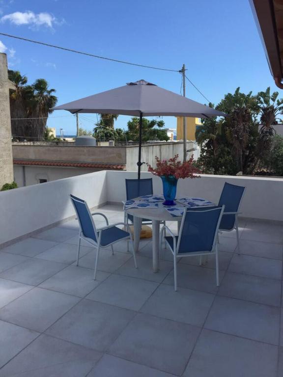 un patio con mesa, sillas y sombrilla en Casa vacanze Francesca sul mare, en Mazara del Vallo