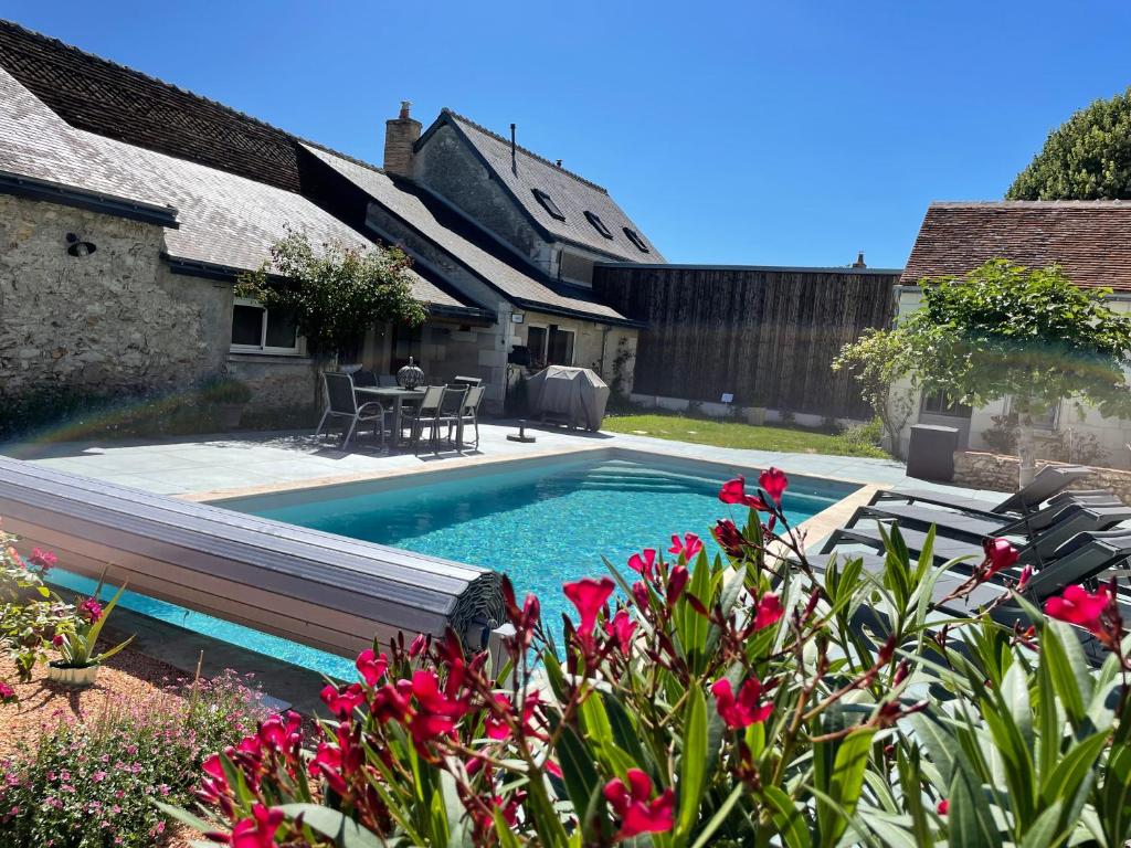 a swimming pool in the backyard of a house with pink flowers at Le Clos des Buis 2 gîtes 6CH 4 SDB 4 WC in Azay-sur-Cher