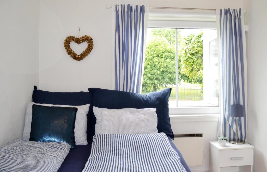 a bed with blue and white pillows and a window at Endless Summer in Tønsberg