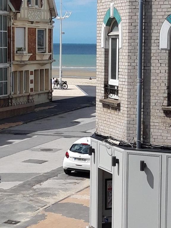 une voiture blanche garée dans une rue à côté d'un bâtiment dans l'établissement Petit studio vue mer 50m de la plage Malo, à Malo-les-Bains