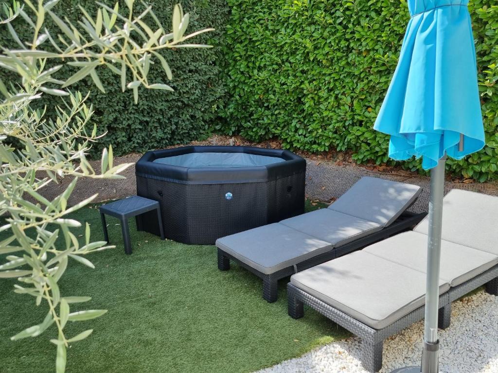 an umbrella and a bench and a trash can at Petit nid douillet en Luberon avec spa in Ansouis