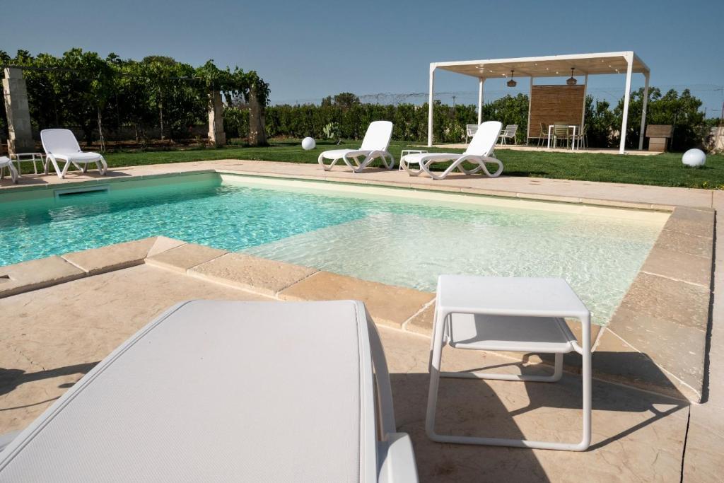 uma piscina com duas cadeiras e uma mesa e uma mesa e cadeiras em IL NOCE Salento Tourism Services em Nardò