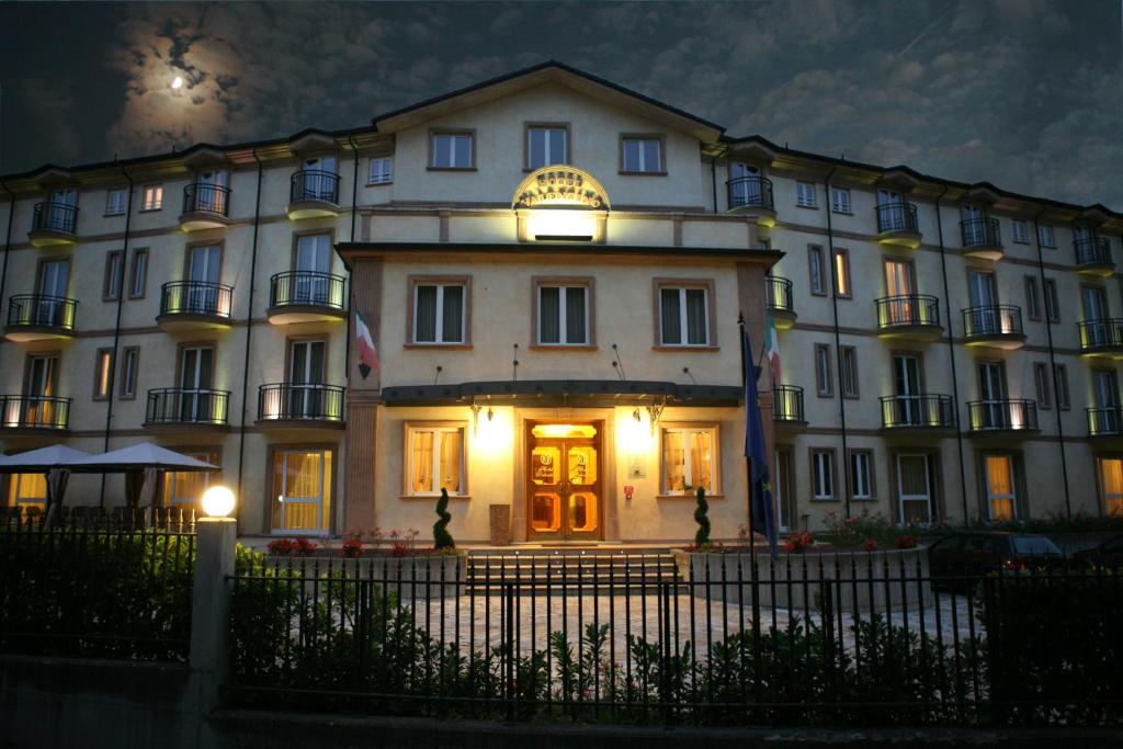 un gran edificio blanco por la noche con luces encendidas en Hotel Valentino, en Acqui Terme