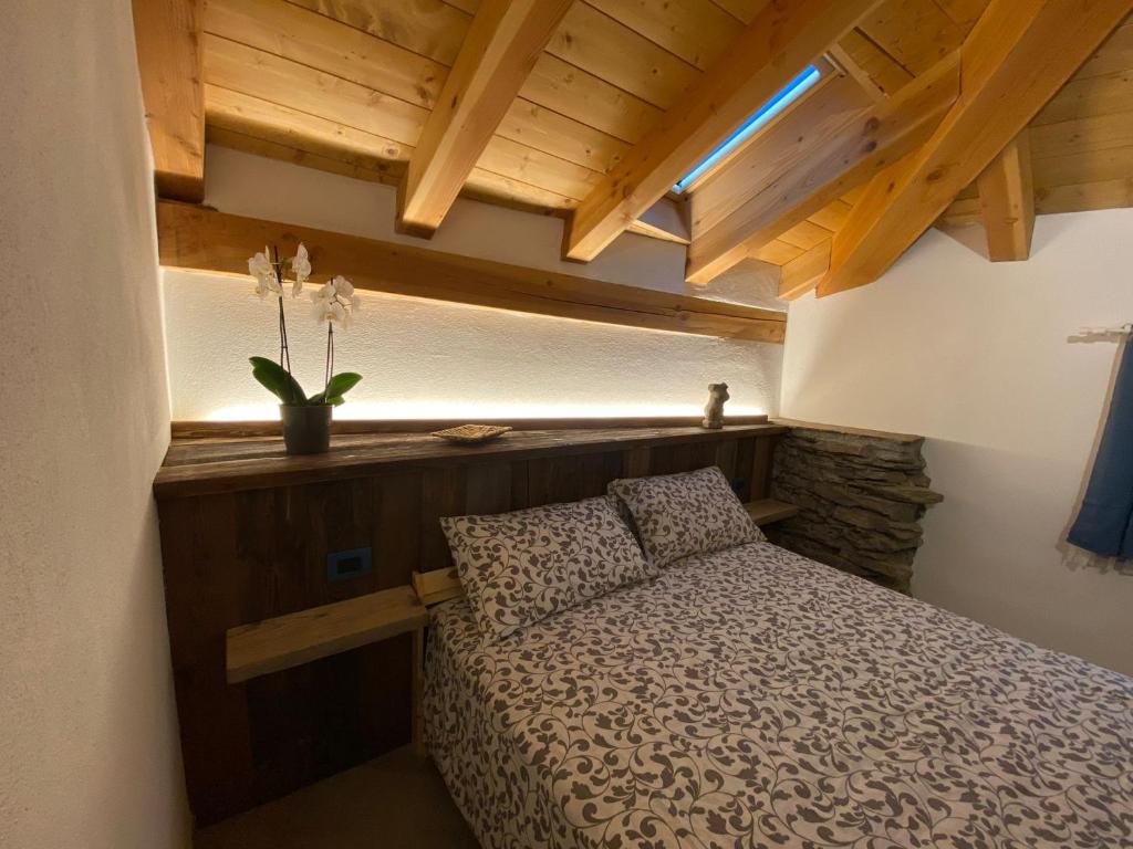 ein Schlafzimmer mit einem Bett in einem Zimmer mit Holzdecken in der Unterkunft Chez Orsille in Aymavilles