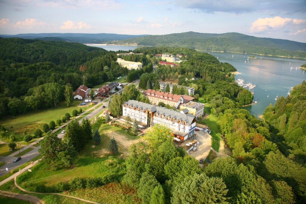 an aerial view of a building on a hill next to a lake at Hotel Skalny Spa Bieszczady in Polańczyk
