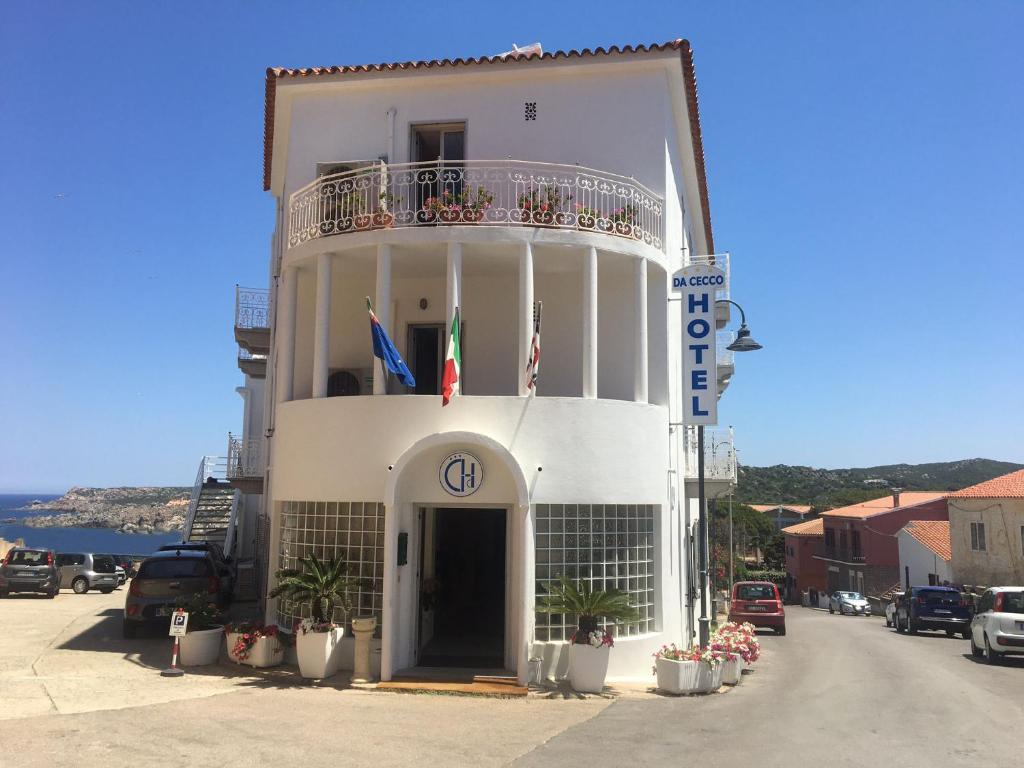 un edificio blanco con balcón y banderas. en Hotel Da Cecco, en Santa Teresa Gallura