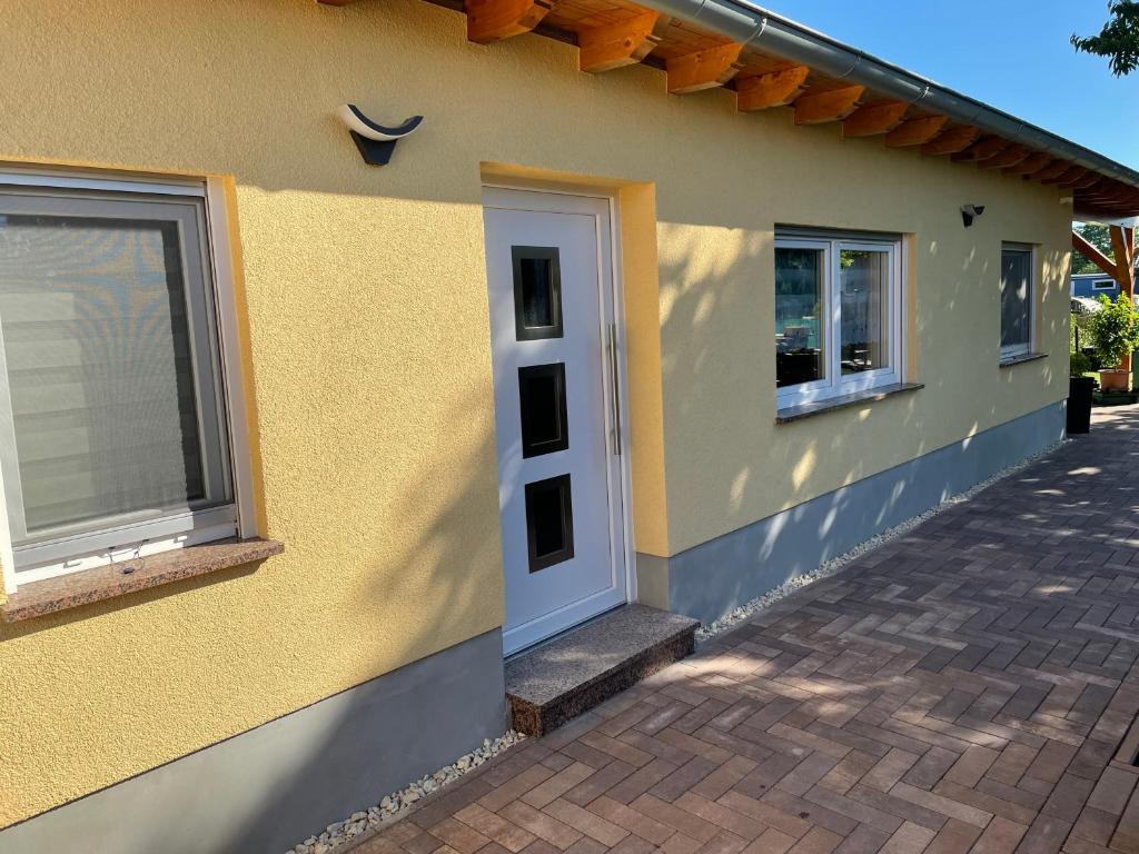 Casa amarilla con puerta blanca y ventanas en Ferienwohnung Arthur, en Luckenwalde