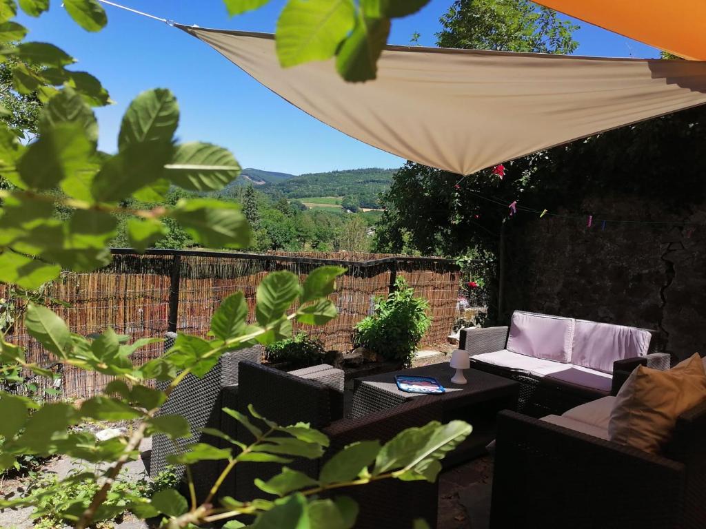 un patio con sombrilla y una mesa con una silla en Maison au coeur du village de la Salvetat sur Agout, en La Salvetat-sur-Agout