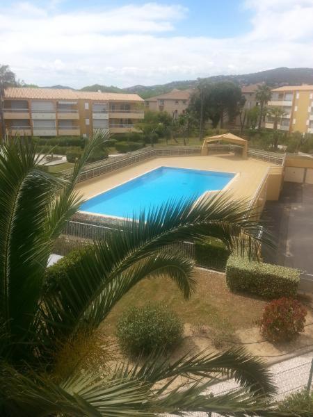 - une vue sur la piscine bordée de palmiers et de bâtiments dans l'établissement Le lavandou rdj avec piscine résidence Le Lavandor, au Lavandou