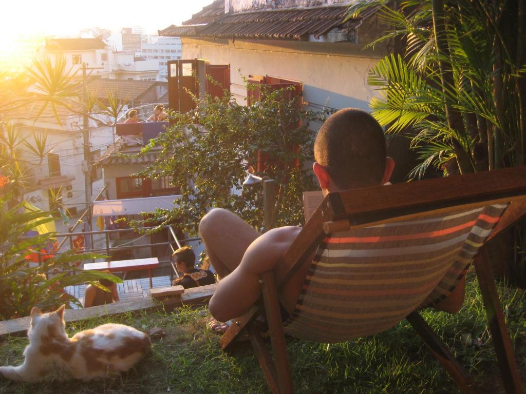 a man sitting on a bench next to a dog at Mambembe Hostel in Rio de Janeiro