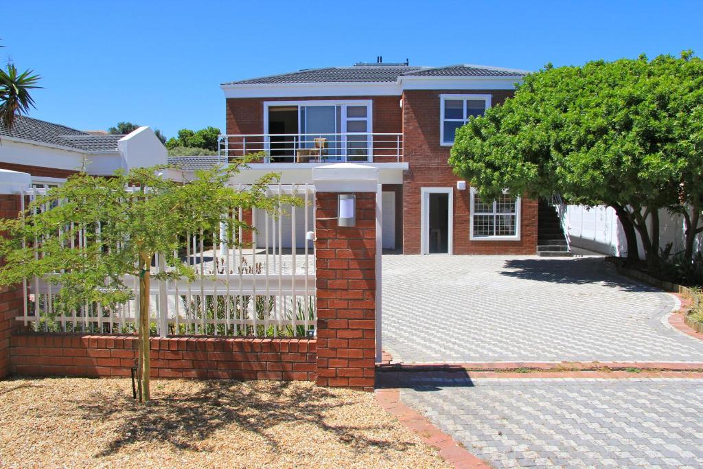 une maison en briques rouges avec une clôture blanche dans l'établissement Lazy Days Apartments - Cape Town, au Cap