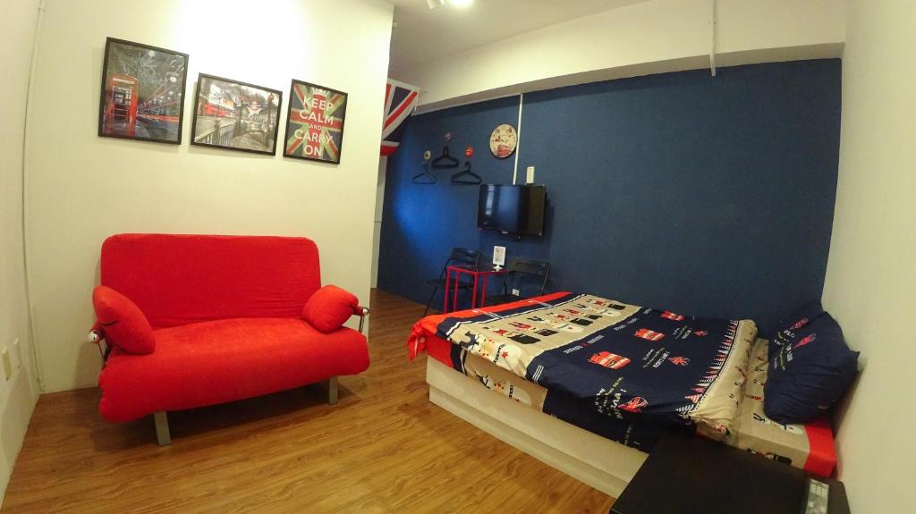 1 dormitorio con 1 cama y 1 silla roja en 心旅地圖青年旅館, en Changhua City