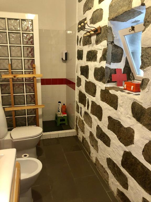 a bathroom with a toilet and a stone wall at Casa Auri in Faial da Terra