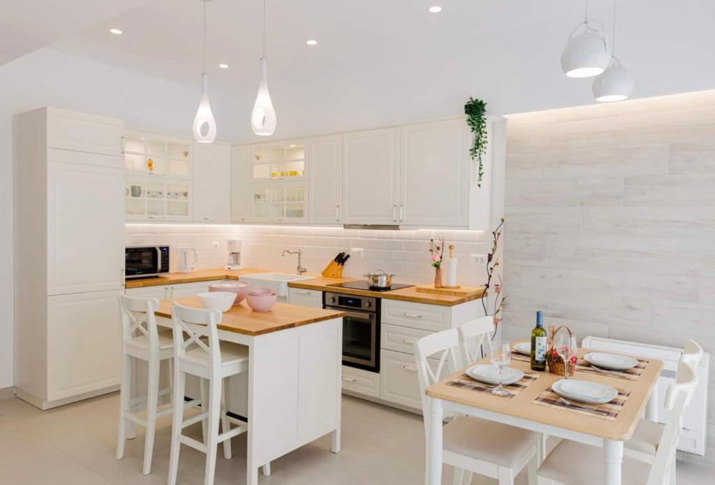 コス・タウンにあるOld town luxury apartmentの白いキャビネット、テーブルと椅子付きのキッチンが備わります。