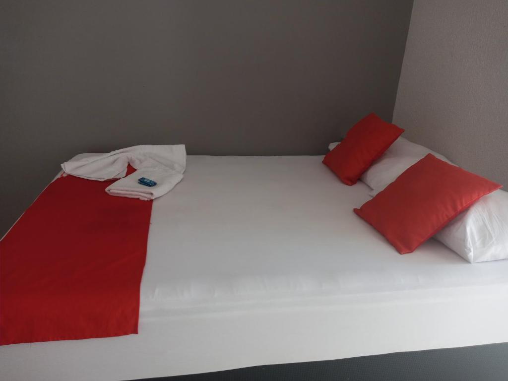 1 cama con almohadas rojas y blancas en Hotel Central, en Jacareí