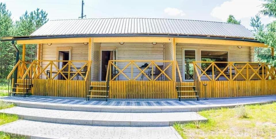 una grande casa gialla con un ampio ponte di Kaimo turizmo sodyba Ramybės oazė ad Antakalnis