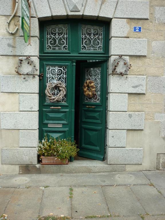 zielone drzwi na budynku z dwoma doniczkami w obiekcie La Maison de Claire w mieście Val Couesnon