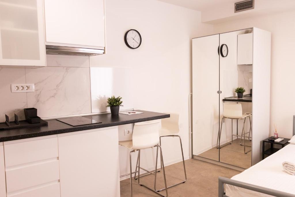 eine Küche mit weißen Schränken und einer Theke mit Stühlen in der Unterkunft Koper2stay Apartments in Koper
