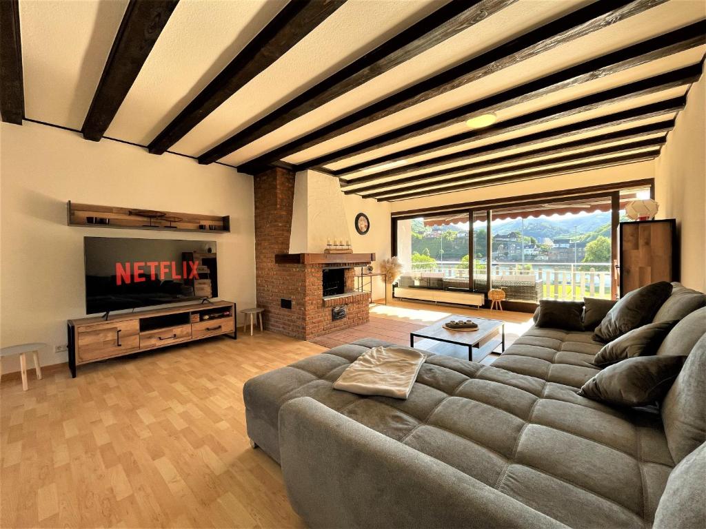a living room with a couch and a television at Traumaussicht Kamin Balkon Burgblick 65 Zoll TV Netflix Sky Joyn Lindenplatz in Bullay