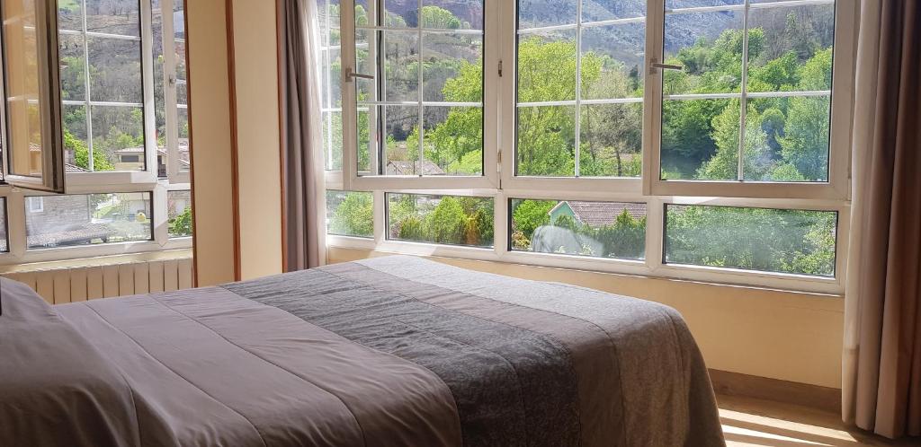 a bedroom with large windows with a bed in front of it at Hotel Naranjo De Bulnes in Arenas de Cabrales