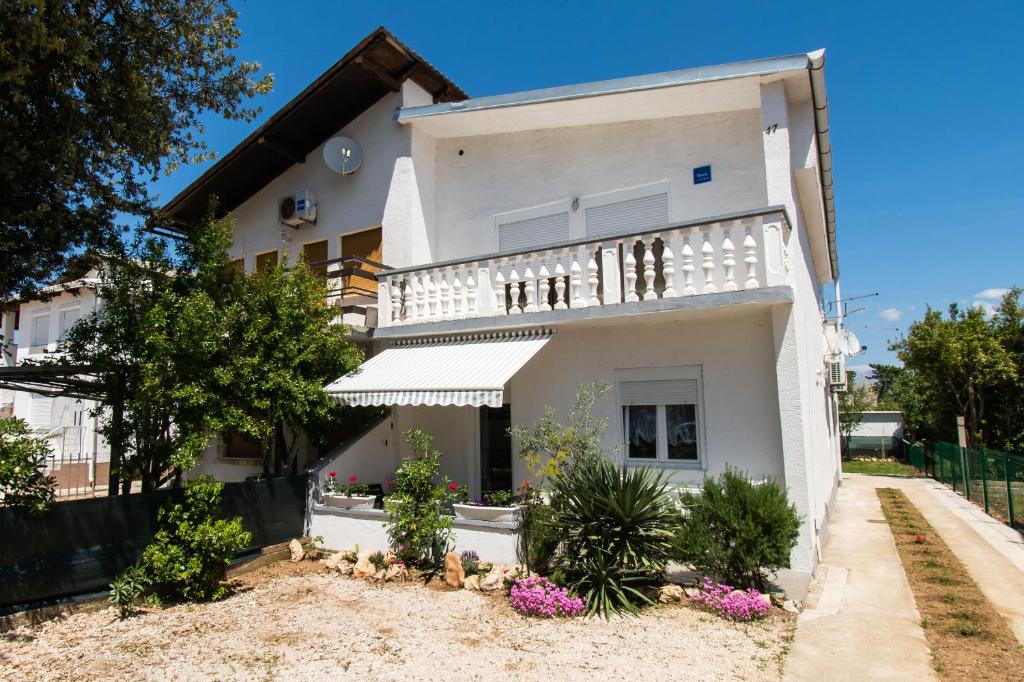 une maison blanche avec un balcon et des fleurs dans l'établissement Apartments Lily, à Batalaži