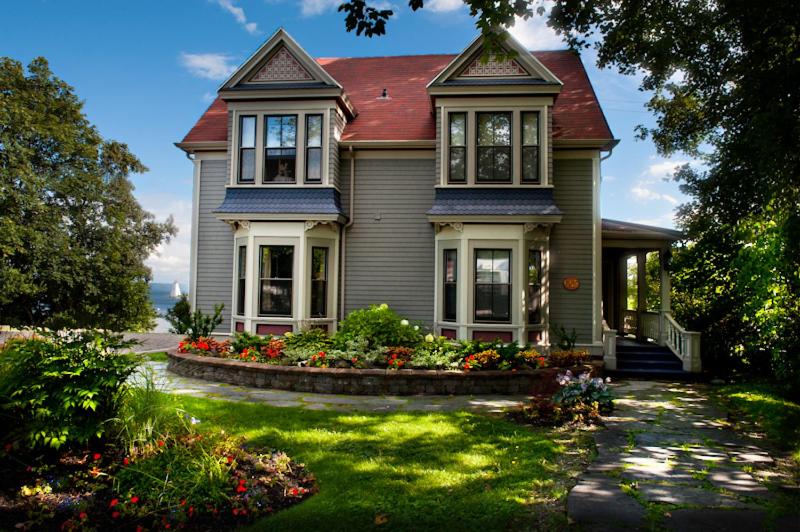 una casa con un jardín con flores delante en Dunlop Inn, en Baddeck