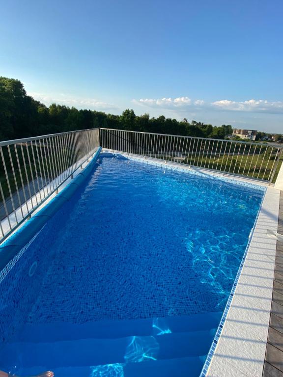 a swimming pool with blue water and a fence at Birutės parko apartamentai in Palanga
