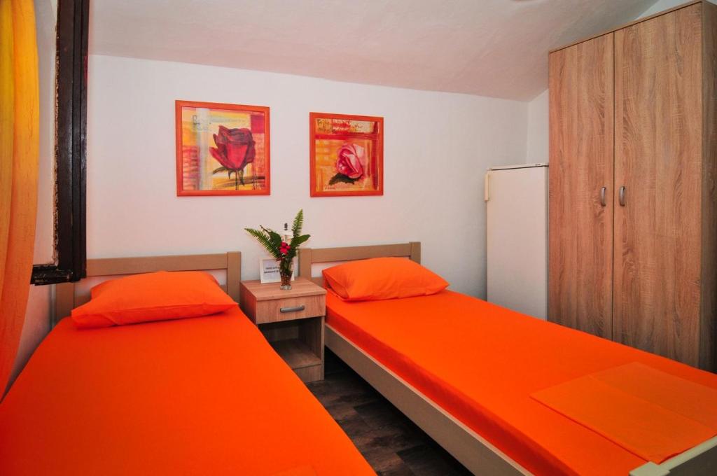 two beds in a room with orange sheets at Sofia Rooms in Tivat