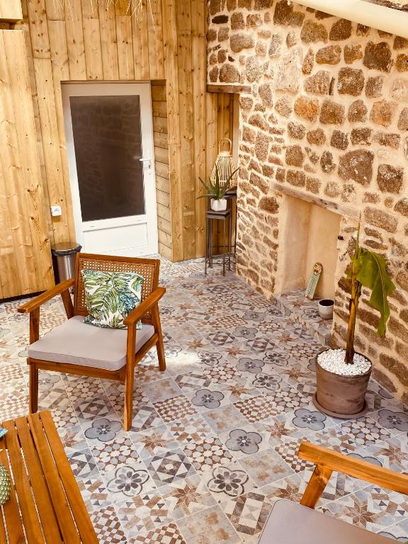 a living room with a stone fireplace and a chair at Gîte « Le Patio » in Montfarville