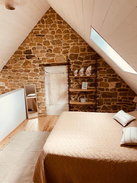 a bedroom with a large bed in a stone wall at Gîte « Le Patio » in Montfarville