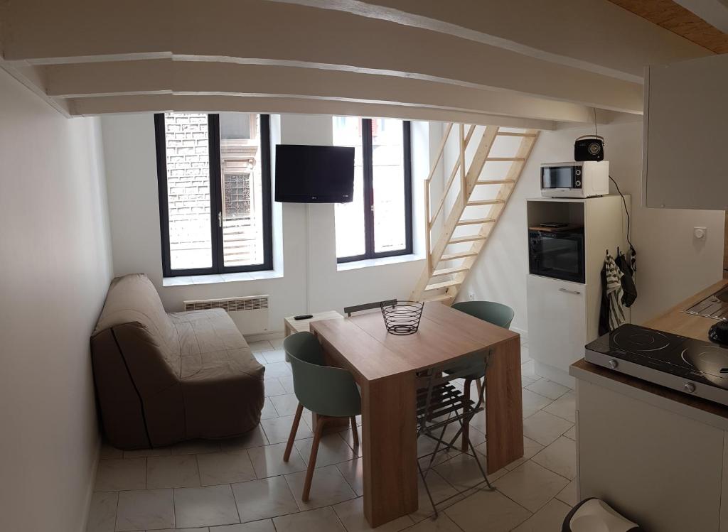 une cuisine avec une table et des chaises dans une pièce dans l'établissement studio les volets bleus, à Boulogne-sur-Mer