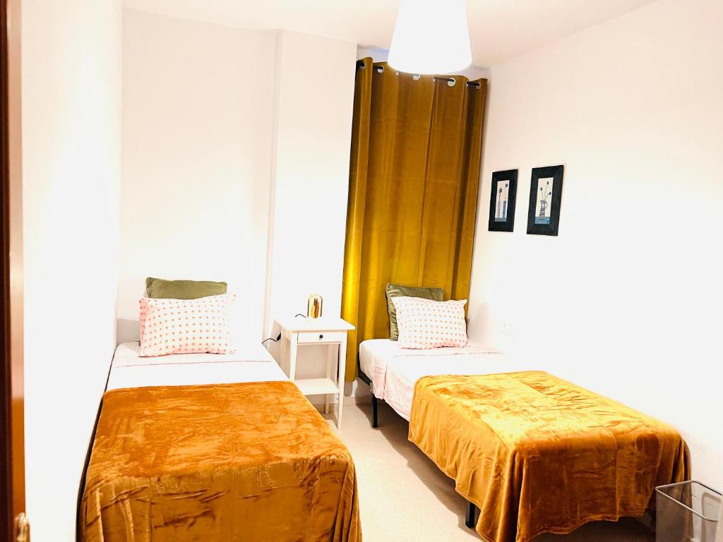 a room with two beds with orange sheets in it at Apartamento Rincón, Ideal para familias in Cala del Moral