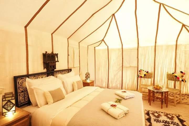a bedroom with a large bed with two towels on it at Zagora luxury desert camp in Zagora