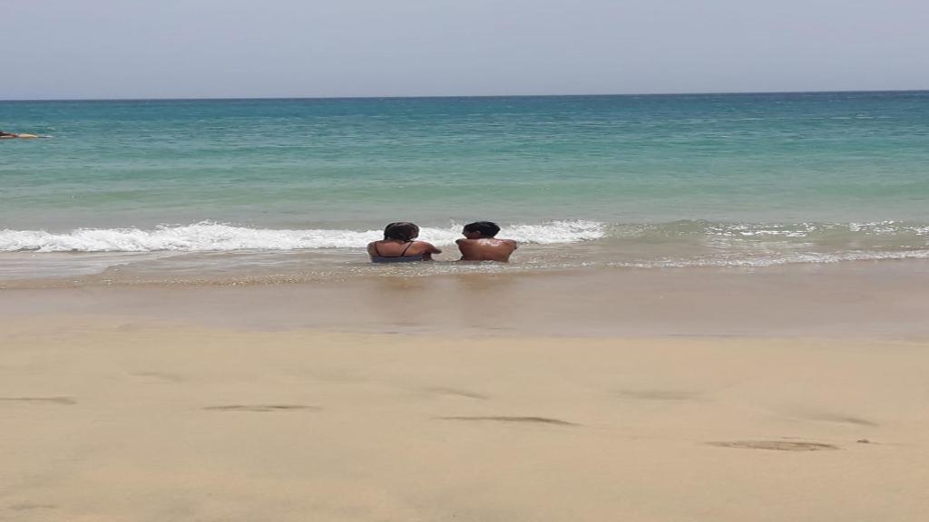 two boys are sitting in the water on the beach at Cyelo Powered by SolymarCalma in Costa Calma