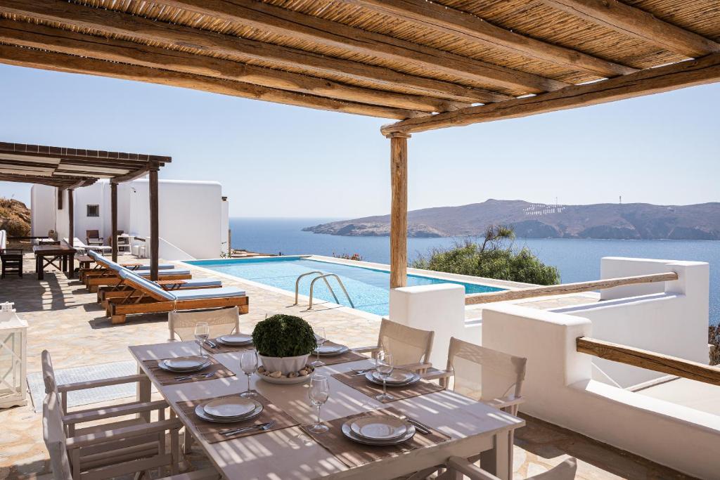 a dining table and chairs on a patio with a pool at Estia's Residence in Mikonos