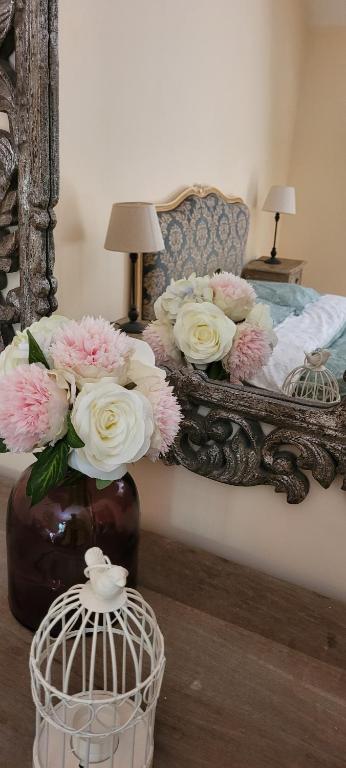 Un dormitorio con una cama con un jarrón de flores en La Grange, Le Domaine de Brugal, en Carsac-Aillac