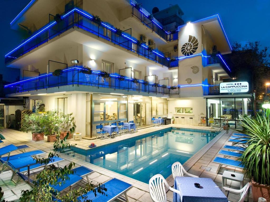 a hotel with a swimming pool in front of a building at Hotel La Cappuccina in Riccione