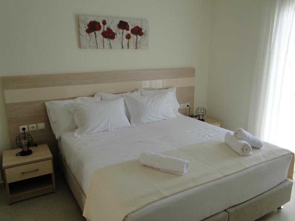 a bedroom with a white bed with two towels on it at Chrysanthe's Apartments No2 in Poros