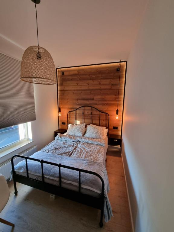 um quarto com uma cama e uma cabeceira em madeira em Komfortowy apartament przy lesie em Wejherowo