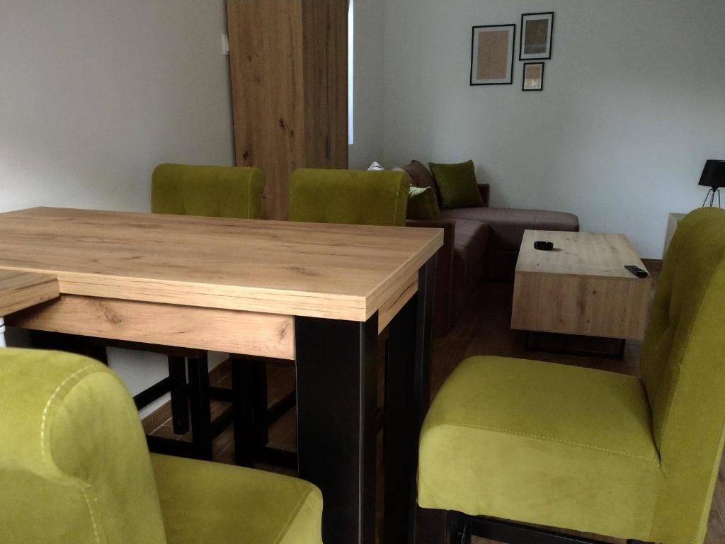 una sala de conferencias con mesa de madera y sillas verdes en Smestaj Stanisavljevic, en Soko Banja