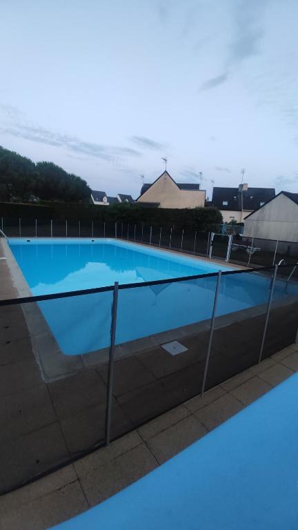 a blue swimming pool behind a fence at Maison bord de mer à St Gildas de Rhuys in Saint-Gildas-de-Rhuys