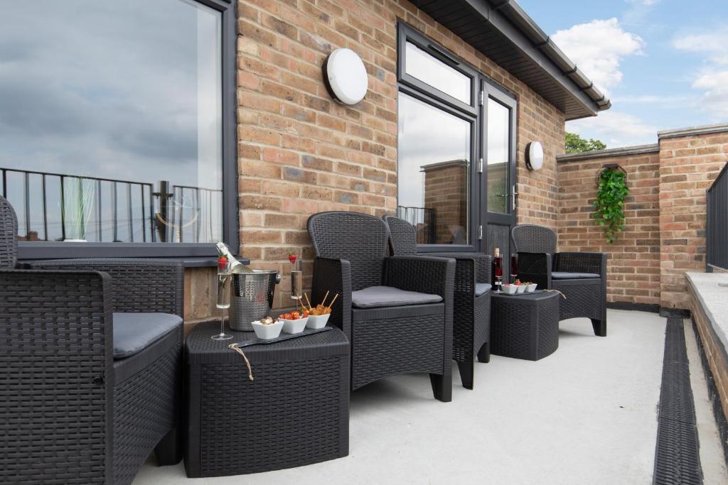 a patio with wicker chairs and tables on a balcony at homely - North London Apartments Wembley in Harrow on the Hill