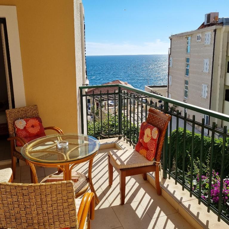 a balcony with a table and chairs and the ocean at Apartments Rales in Sveti Stefan